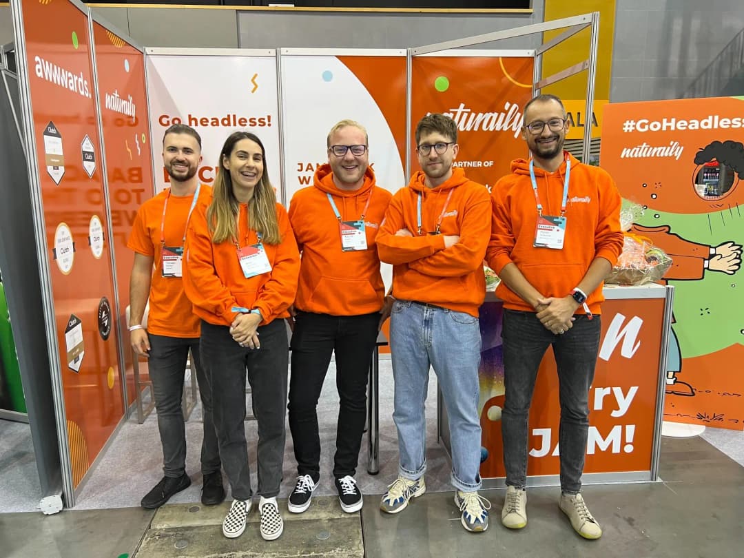 Naturaily employees standing in front on their event booth, wearing orange hoodies