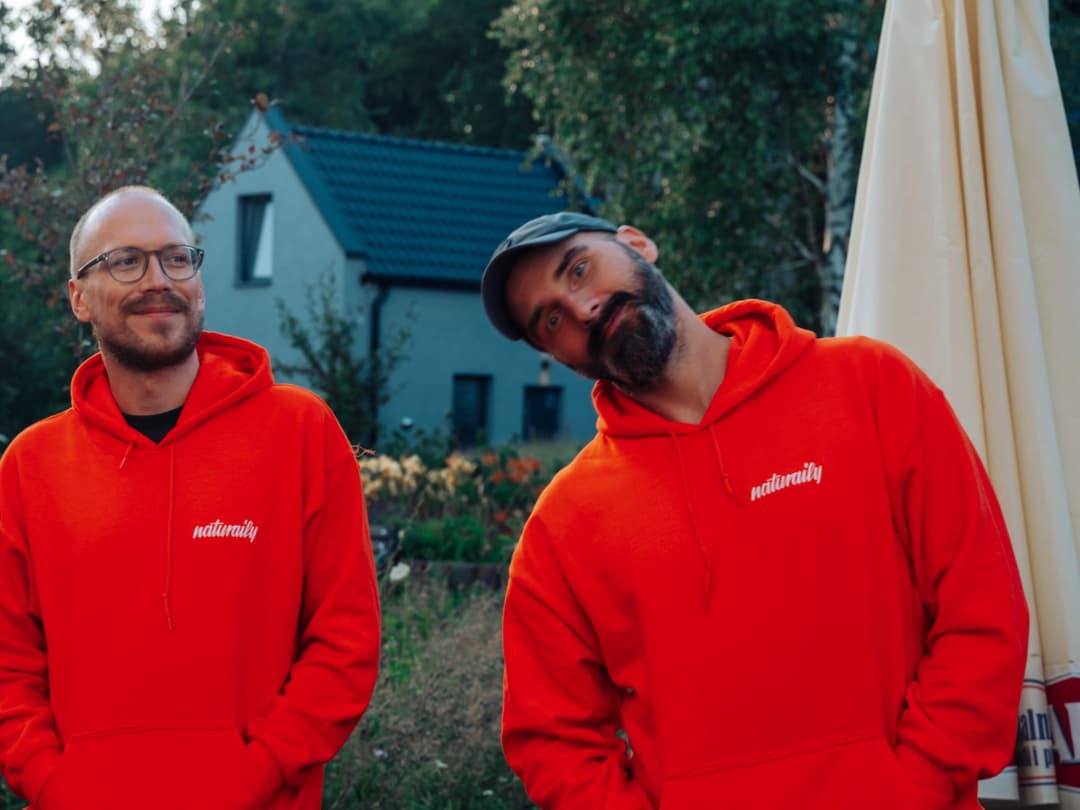 Naturaily employees smiling to the camera, while standing in the forest dressed in the Naturaily branded hoodies